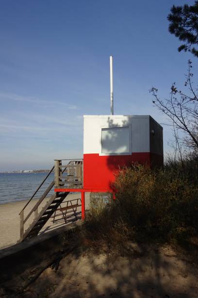 istock Red and white wooden lifeguard cabin with a stair on an empty sandy beach in Pirita. Empty beach with no people on a sunny day. Tallinn, Estonia. October 2021 1348835989