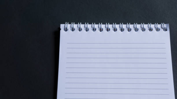 istock minimal work space, top view of note book on black background. note book copy space and text space 1348837644