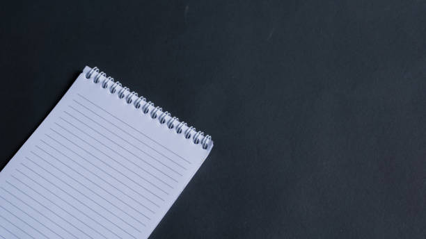 istock minimal work space, top view of note book on black background. note book copy space and text space 1348837647