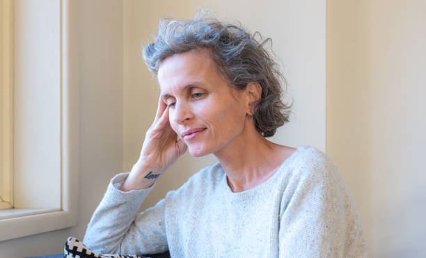 istock Middle aged woman resting head on hand and smiling 1348838056