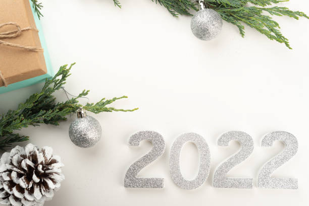 istock Flat lay with 2022 numbers, Christmas tree branches, pine cones, Christmas baubles, presents on light background. 1348845875
