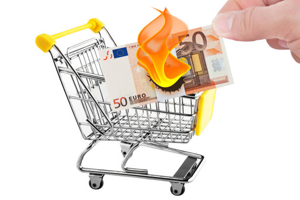 Male hand holds 50 euro banknote in shopping cart which burns up concept inflation stock photo