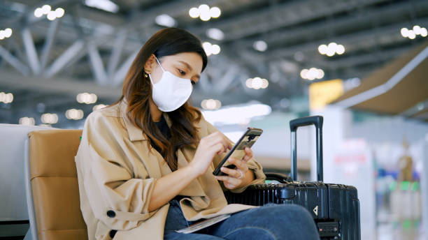 istock Traveler  with face mask using mobile phone in airport . 1348851714