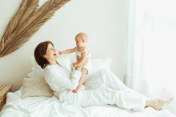 istock Mother and child on a white bed playing in sunny bedroom 1348854041