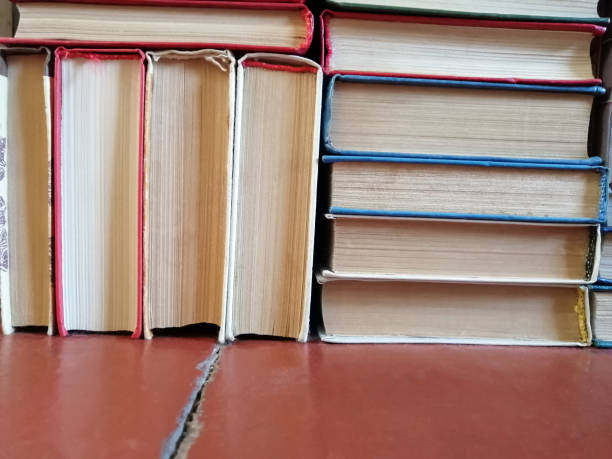 istock Books on the floor stacked chaotically against the wall 1348856440