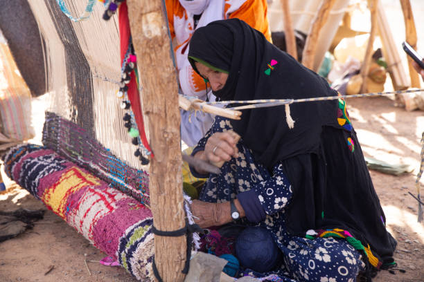 A woman weaves on a traditional loom in the Sahara desert. A woman weaves on a traditional loom in the Sahara desert, Morocco moroccan woman stock pictures, royalty-free photos & images