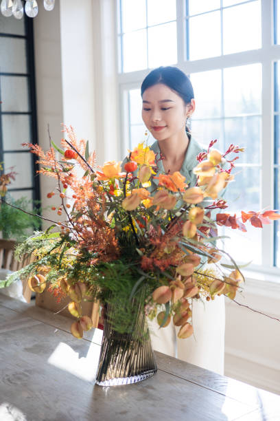 istock Woman arranging flowers at home 1348861659