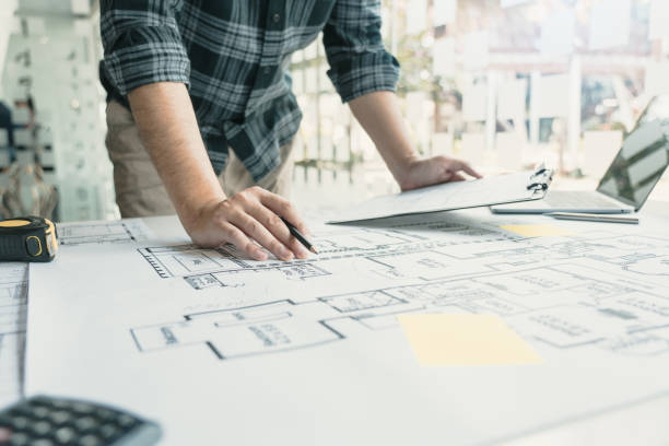 istock Interior designer or architect reviewing blueprints and holding pencil drawing on desk at home office. 1348863436