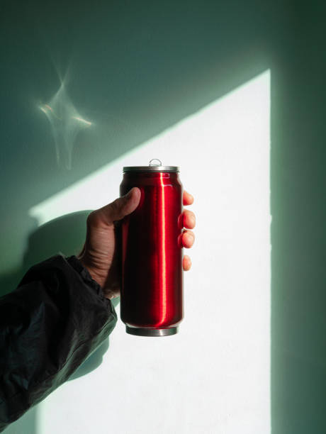 istock Red thermo can bottle in male hands against wall with harsh shadow.Hot tea coffee drinking in cold autumn winter weather 1348863507