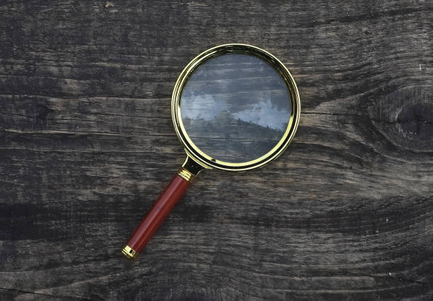 istock Magnifying glass on wood aged weathered background. Magnification concept 1348865914