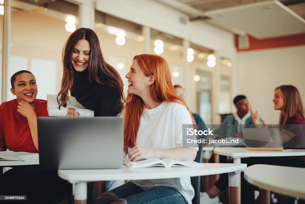 University students in classroom after lecture Female student talking with classmates and smiling in lecture room. University students in classroom after lecture. University Student Stock Photo