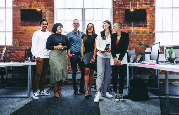 feliz grupo de empresarios riendo en una oficina - diferentes edades fotografías e imágenes de stock