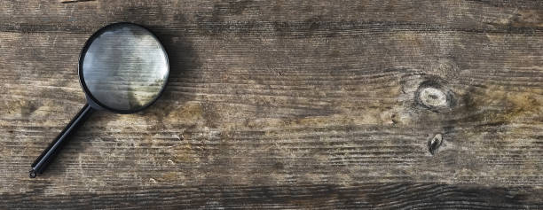 istock Magnifying lens on wood aged background with copy space for text. Wooden horizontal banner with copyspace 1348871777