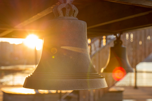 Sunlight through old bells with sun flare at golden sunset. Blurred vintage background