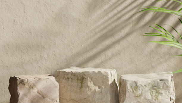 Three mockup boulders against a beige stone wall. Stage for product presentation. Shallow depth of field. 3D render.