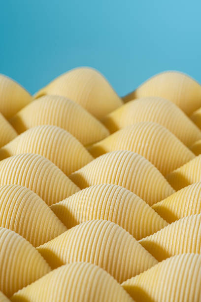 istock Abstract creative food concept. Dry uncooked pasta conchiglioni or conchiglie with blue background 1348874182