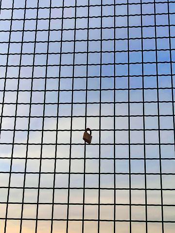 metal padlock on a wire mesh with sky, space for text, copy space