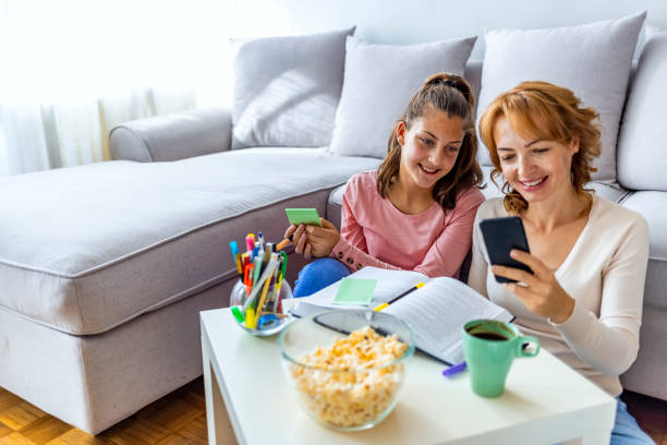 istock Mother using smart phone and helping daughter with homework 1348881714