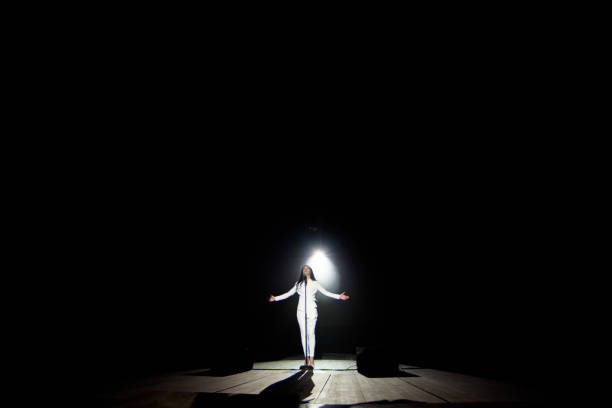 istock Young woman with microphone and white lights on a concert 1348884204