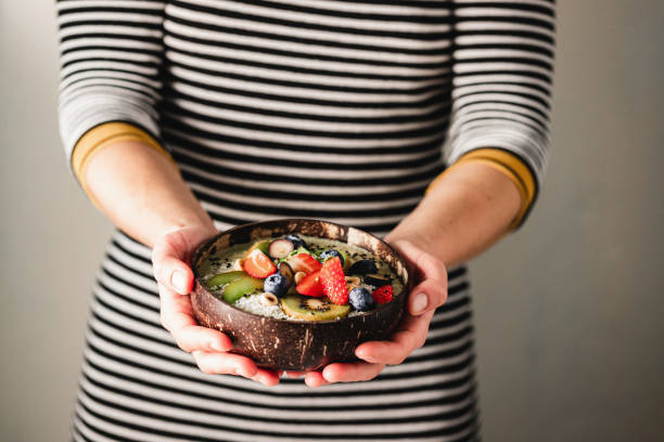 Woman holding mixed fruit smoothie bowl