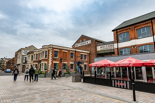 People walk and visit the shops and restaurants at historic warehouses in Gloucester Docks