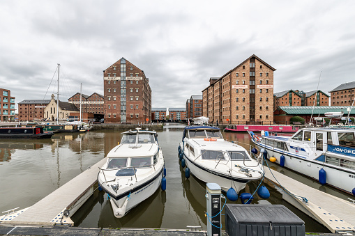 Boats moored in historic Gloucester Docks with warehouses behind.