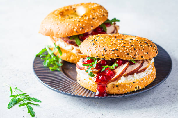 thanksgiving-food-konzept. bagel-sandwich mit truthahn und cranberrysauce auf einem grauen teller. - sandwich turkey cranberry cheese stock-fotos und bilder