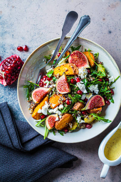 calda insalata autunnale di quinoa con verdure al forno, fichi, formaggio feta e melograno. - brussels sprout vegetable organic healthy eating foto e immagini stock