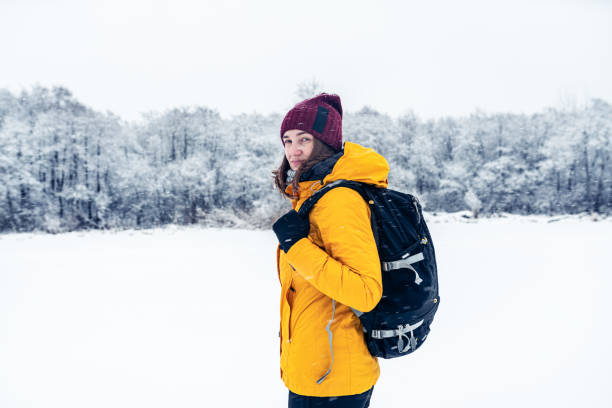 istock Woman with backpack on a winter walk outdoors. Defocused winter forest on background. 1348897764