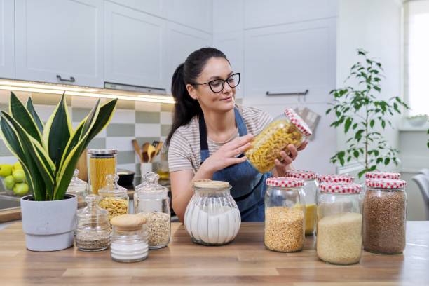 comida, almacenamiento de comestibles, mujer sonriente mirando a la cámara en la cocina. - oatmeal oat box container fotografías e imágenes de stock