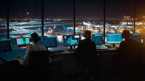 Diverse Air Traffic Control Team Working in Modern Airport Tower at Night. Office Room Full of Desktop Computer Displays with Navigation Screens, Airplane Departure and Arrival Data for Controllers. Diverse Air Traffic Control Team Working in Modern Airport Tower at Night. Office Room Full of Desktop Computer Displays with Navigation Screens, Airplane Departure and Arrival Data for Controllers. atc stock pictures, royalty-free photos & images