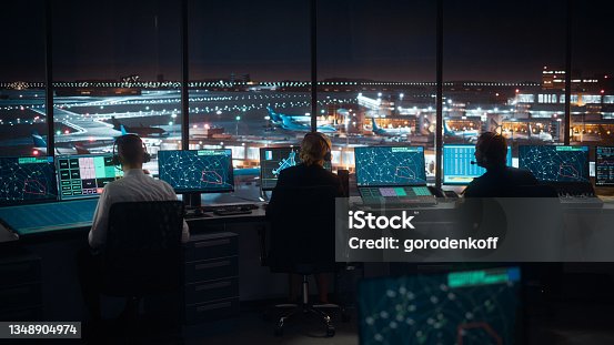 istock Diverse Air Traffic Control Team Working in a Modern Airport Tower at Night. Office Room is Full of Desktop Computer Displays with Navigation Screens, Airplane Flight Radar Data for Controllers. 1348904974