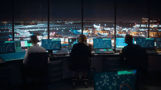 diversas equipes de controle de tráfego aéreo trabalhando em uma torre moderna do aeroporto à noite. a sala de escritório está cheia de monitores de computador de mesa com telas de navegação, dados de radar de voo de avião para controladores. - controle - fotografias e filmes do acervo