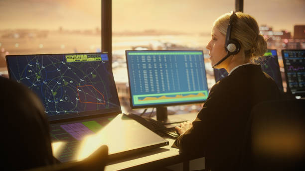 空港タワーでヘッドセットを持つ女性の航空管制官が話します。デスクトップコンピュータのフルオフィスルームは、ナビゲーション画面、コントローラのための飛行機のフライトレーダー� - air traffic control tower ストックフォトと画像