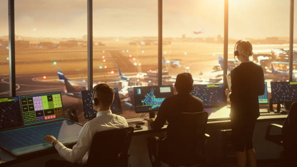 diverse air traffic control team working in a modern airport tower at sunset. office room is full of desktop computer displays with navigation screens, airplane flight radar data for controllers. - air vehicle audio imagens e fotografias de stock