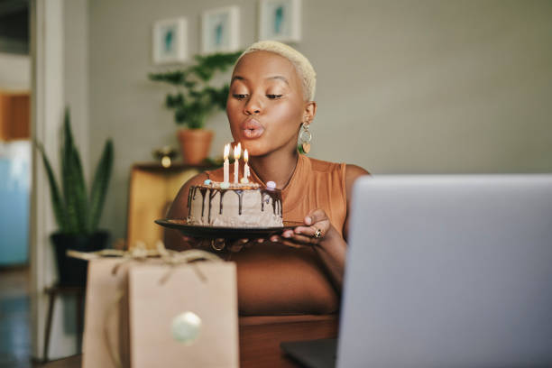 ラップトップ上のビデオ通話中に誕生日ケーキキャンドルを吹き飛ばす女性 - cake birthday candle blowing ストックフォトと画像