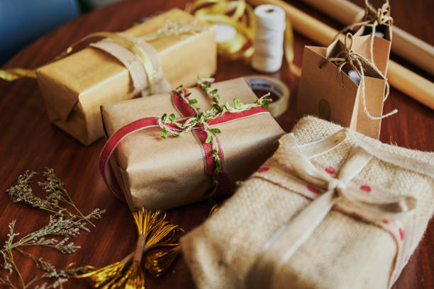 Variety of Christmas presents wrapped in the environmentally friendly paper Variety of Christmas presents and in environmentally friendly wrapping paper sitting on a table during the holidays christmas paper photos stock pictures, royalty-free photos & images