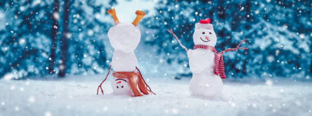 istock Cheerful snowmen standing in magical winter forest 1348931567