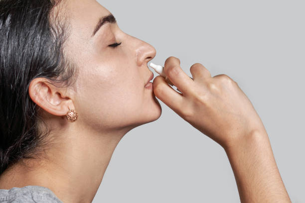 Woman using nasal spray Woman using nasal spray. A woman using a nasal spray to decongest her nose. Sick woman using nasal spray. Woman using nose spray nasal spray stock pictures, royalty-free photos & images