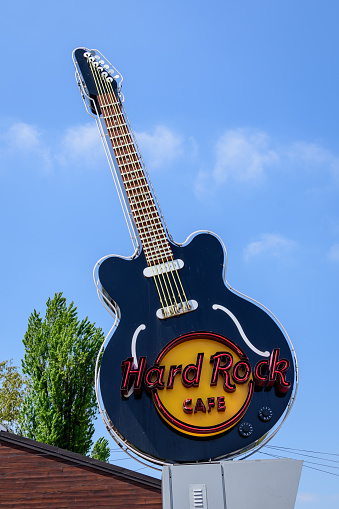 Bucharest, Romania - 30 April 2021: Big black guitar displayed at the entry to Hard Rock Café American style restaurant in King Michael I Park (Herastrau), in a sunny spring day