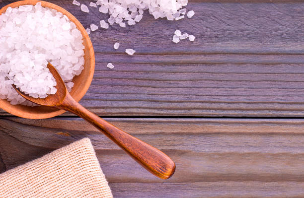 istock white sea salt on cup, spoon and burlap on a wooden table. 1348936339