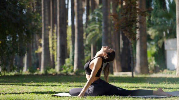 istock Young woman practicing yoga in a public park 1348936816