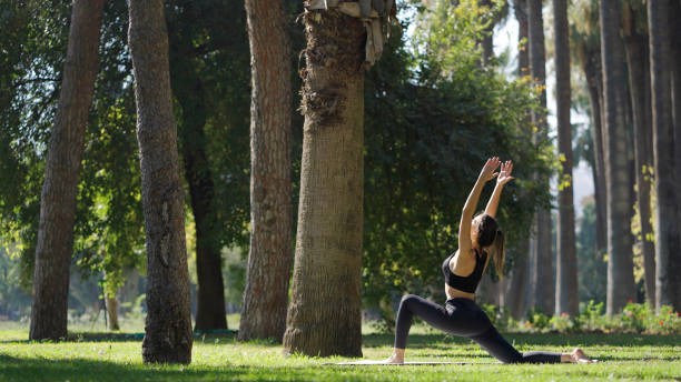 istock Young woman practicing yoga in a public park 1348936958