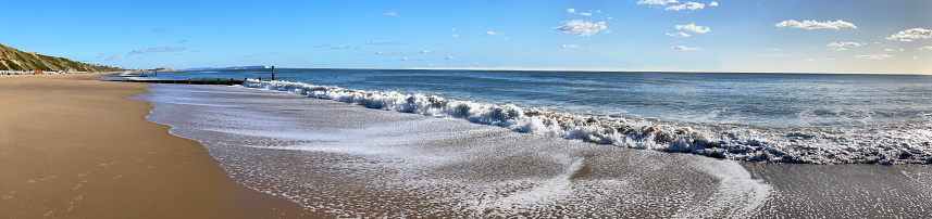 Gentle waves break and lap against the shoreline at the waters edge of this south coast sandy beach, Poole Bay, Dorset, England, UK