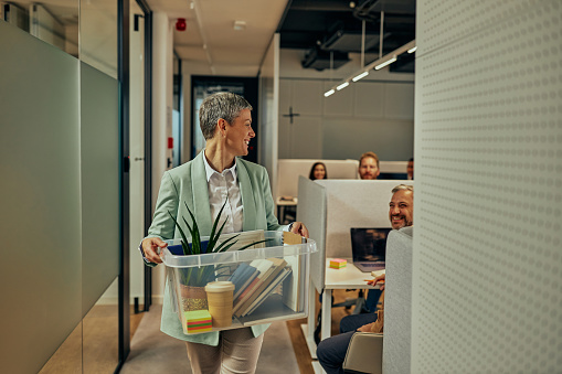 Whole collective greets their colleague who return back to work and holding box with ofiice supllies