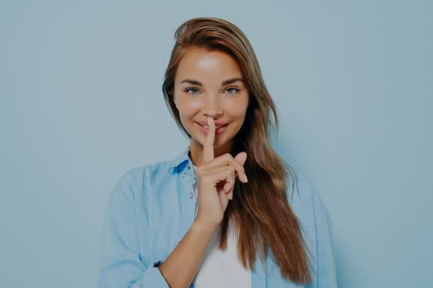 istock Beautiful woman showing shush gesture on light blue background 1348941809