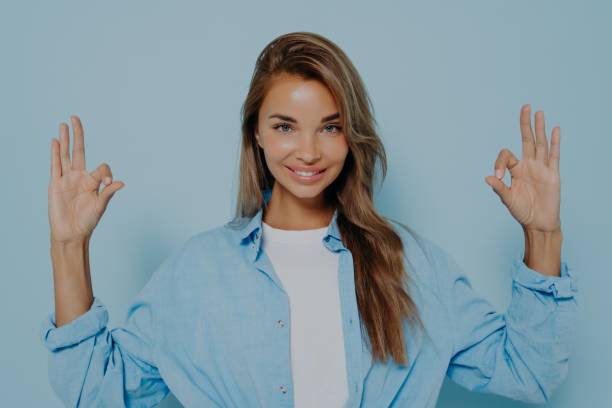 istock Charming woman making okay gesture against light blue background 1348941820