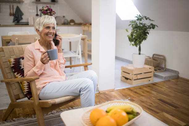 istock Old woman talking on mobile phone and holding coffee mug 1348943995