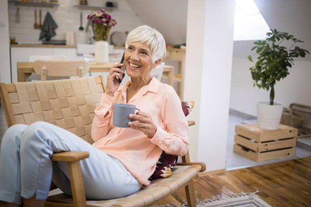 istock Senior woman sitting on sofa and using mobile phone 1348943998
