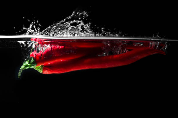 istock Red chili peppers falling into the water isolated 1348947501